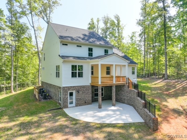 Back of house with a lawn and a patio