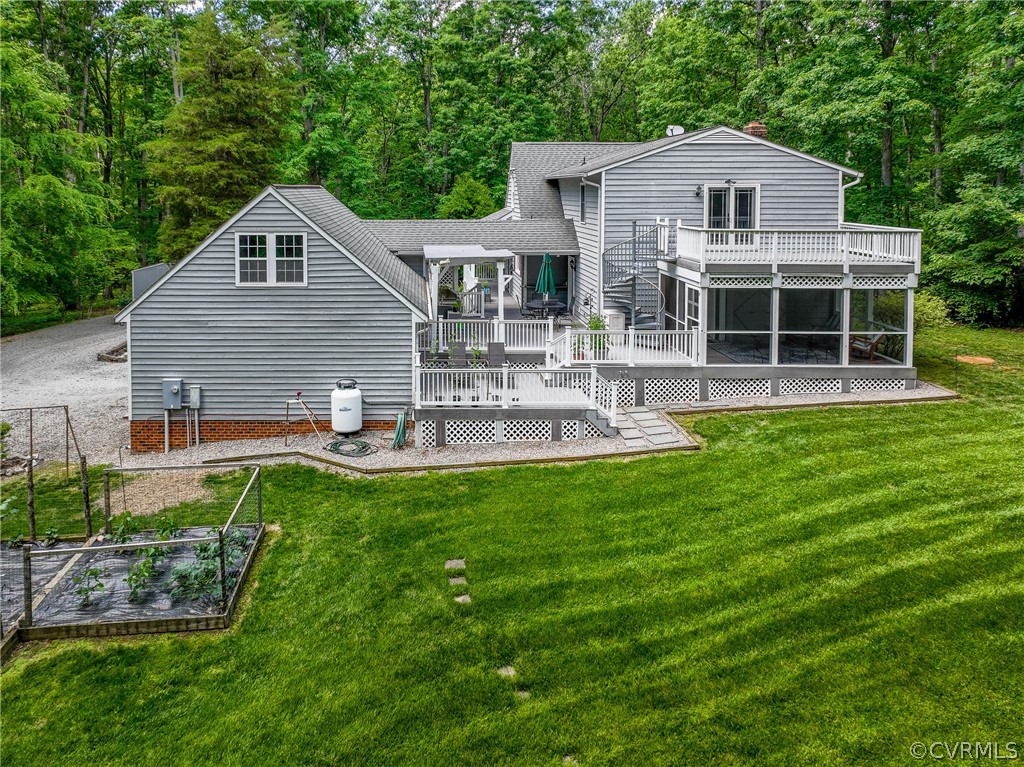 Back of property with a balcony, a lawn, and a  de