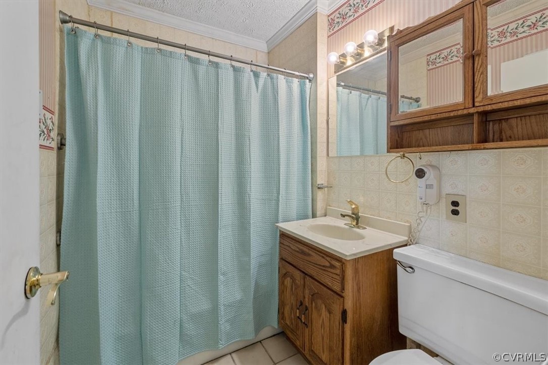 Bathroom with tile walls, toilet, crown molding, v