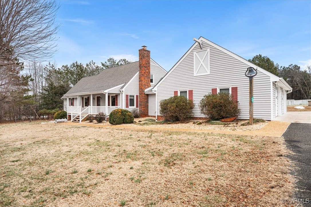 View of side of home featuring a yard, covered por