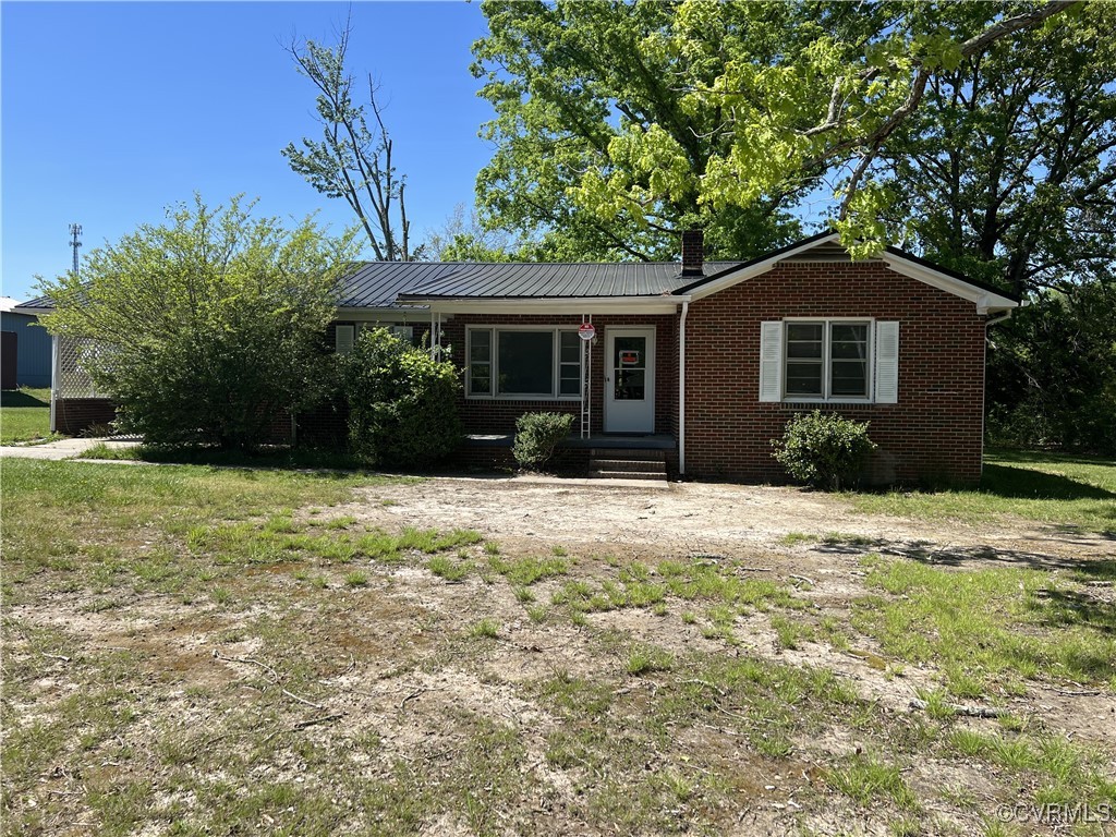 Ranch-style home with brick siding, a chimney, and