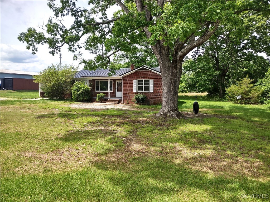Ranch-style house with a chimney, brick siding, a