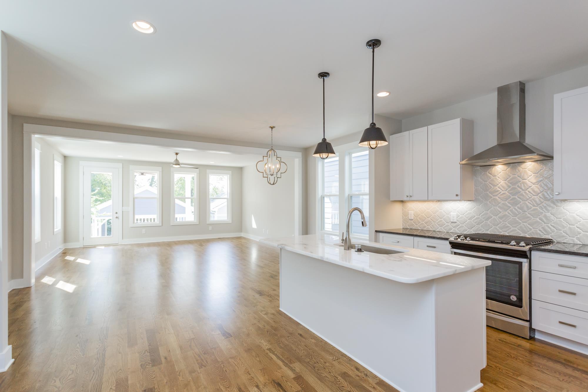 Magnificent bright  kitchen with a huge island. Gas stove stainless steel hood. Under mount lighting and a modern tile backsplash!  